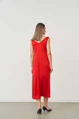 Beautiful woman in a stylish red dress posing in a modern indoor studio setting