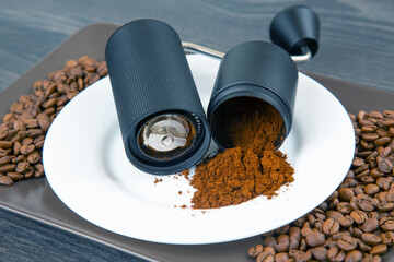Detailed view of a manual coffee grinder, split to reveal freshly ground coffee, with a small spill...