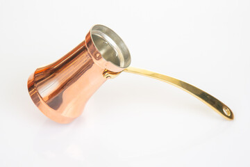Elegant copper Turkish coffee maker with a long brass handle, set against a minimalist white...