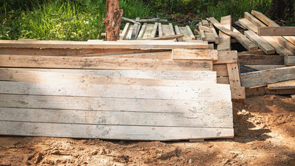 Pile of rough-cut wooden planks ready for construction in a forest location