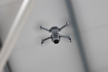 A compact, 249g grey drone hovers from a low angle, its propellers subtly blurred, suggesting it's...