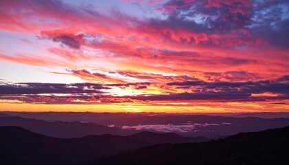 Fototapeta premium Vibrant crimson sunset stretches across cloud edges, layering warm orange and deep rose over a quiet landscape