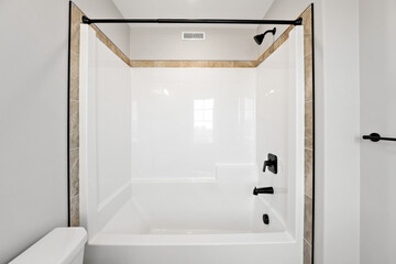 White bathroom with a white bathtub and a black shower head