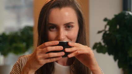 Portrait Caucasian woman smiling drinking hot aroma tasty tea coffee female business girl holding cup sitting in cafe looking at camera cafeteria visitor enjoying breakfast drink happy businesswoman