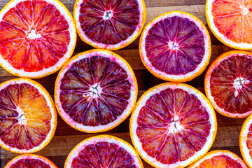 Red blood halved oranges close up on a wood background. Top view. Flat lay of fresh orange citrus...