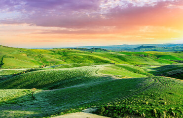 dramatic sunset green landscape in a spring field grassland during evening sunset with green hills...