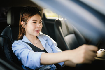 A young Asian woman smiles confidently while driving a modern car, wearing sunglasses and a seatbelt, enjoying a safe, relaxed journey filled with freedom, comfort, and joy.