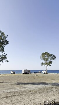 Camping on the seashore, tent, motorhome, boat and tree (vertical)