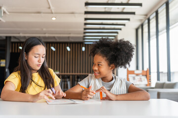 Diverse Young Girls Learning Together at a Table, Children Collaborating on a Project in a...
