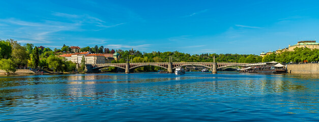 A panorama view along the Vltava river towards the Manes Bridge in Prague in springtime