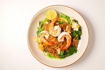 Stir-fried  Thin Rice Noodles with dark Soy Sauce and  shrimp in ceramic plate, top view food table with free copy space