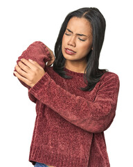 Simple portrait of a young Latina massaging elbow, suffering after a bad movement.