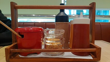 A wooden tray holding condiments, utensils, and a bottle, perfect for food presentation or dining scenes