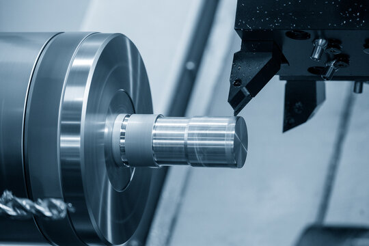 The CNC lathe machine forming cutting the metal shaft parts in the light blue scene.