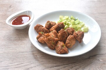 deep fried grouper fish patty on plate with slice cucumber dipping sweet chili sauce 