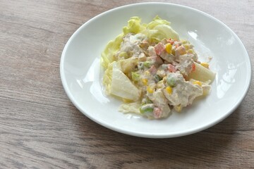 mashed tuna with corn and garden pea couple cabbage vegetable salad dressing cream sauce on plate