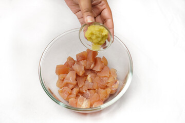 Raw chicken fillet breast cut into pieces and spiced in glass bowl. Small depth of field.