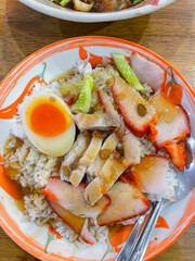 Close up rice crispy pork, roasted red pork, Scallion and boiled egg with sauce in white plate on table background