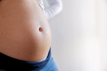 Close-up of a pregnant woman's belly with space to copy text in the background