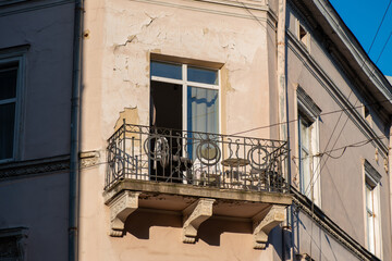 A classic wrought iron balcony on a historic European building with a weathered and peeling paint facade © ronedya
