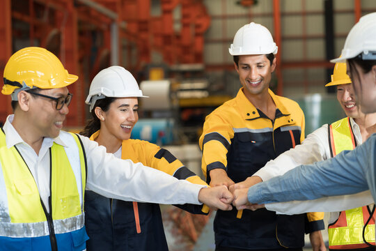 Workers, teamwork and cooperation. Workers join their hands together in industry factory. Unity and teamwork concept