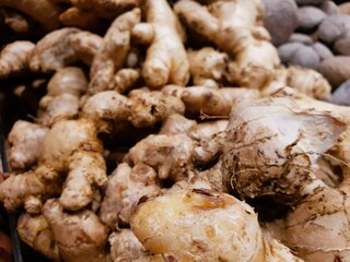 Close-up shot of fresh ginger roots piled high, showcasing their earthy tones and textures. Ideal...