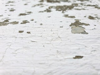 Close-up shot of cracked and peeling white paint on a weathered surface. Shows texture and age....