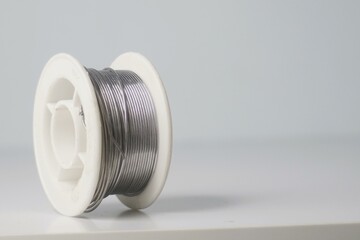 Close-up of a spool of solder wire on a white background. Ideal for electronics, DIY, and repair projects.