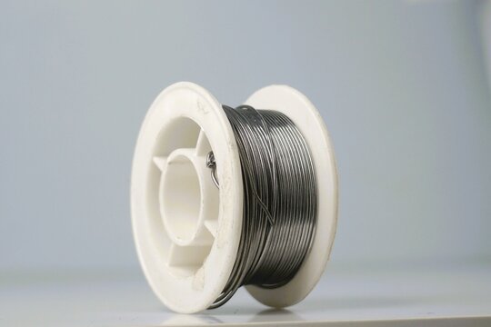 Close-up of a spool of silver solder wire against a white background. Ideal for industrial, electronics, or DIY projects.