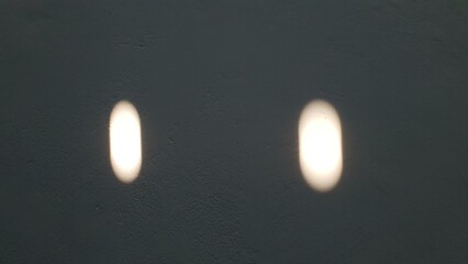 Abstract image of two oval light spots on a dark textured wall. Ideal for backgrounds, textures, or...