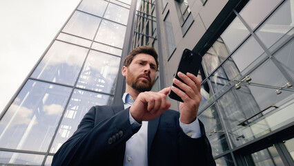 Serious worry anxiety professional male near office building company looking around problem lost in city Wi-Fi connection confused Caucasian man business guy businessman using typing mobile phone