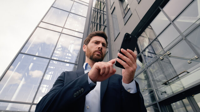 Serious worry anxiety professional male near office building company looking around problem lost in city Wi-Fi connection confused Caucasian man business guy businessman using typing mobile phone