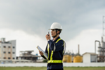 Site Supervisor Using a Walkie-Talkie for On-Site Communication. A man wearing a yellow vest and a...