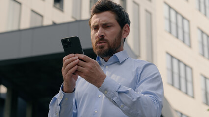 Mad unhappy middle-aged mature businessman man business male feeling annoyed using smartphone in...