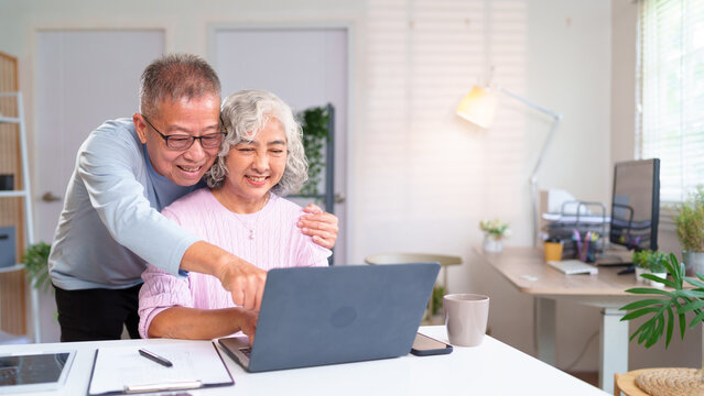 Senior Asian Couple Using Laptop at Home Together Happy Elderly Couple Enjoying Online Content Retirement Lifestyle of Old Asian People - Powered by Adobe