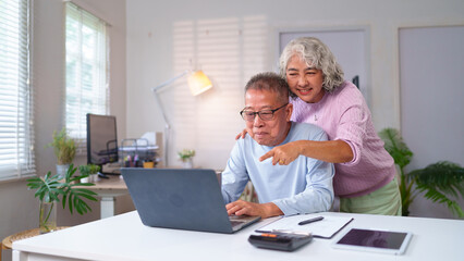 Senior Asian Couple Enjoying Online Time Together at Home Older Couple Using Laptop For Online Shopping Smiling Asian Couple Using Computer