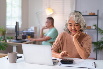 Senior Asian Woman Calculating Finances at Home with Laptop and Calculator, Elderly Couple Managing...