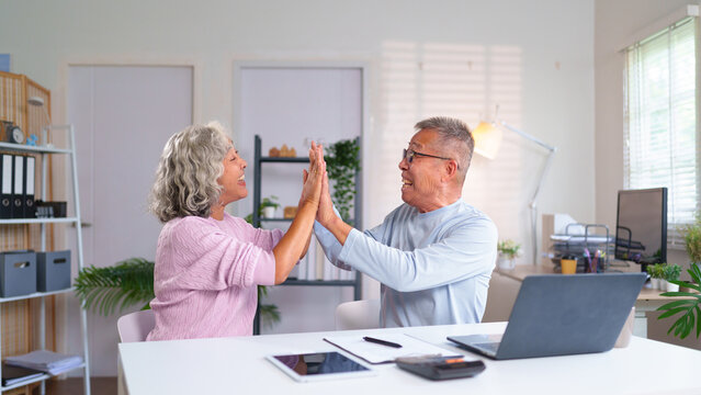 Happy Older Asian Couple Celebrate Success with High Five at Home Office Togetherness Joyful Retirement Lifestyle Elderly Love and Happiness Concept