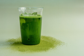 The Matcha green tea glass on a pastel green background, shot in still life style.