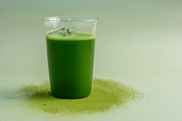 The Matcha green tea glass on a pastel green background, shot in still life style.