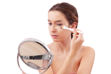 Young woman with natural skin applying foundation with makeup brush while looking into a mirror. Visible foundation streak texture on cheek. Clean beauty routine concept, isolated on white background