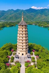 A stunning aerial view of a tall pagoda surrounded by lush greenery and a serene blue lake, ideal for travel articles, cultural references, or nature scenery