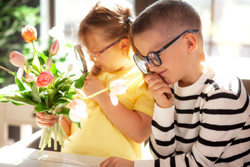 A 7-year-old children in glasses and dresses striped vest, poses at the school table indoor. the...