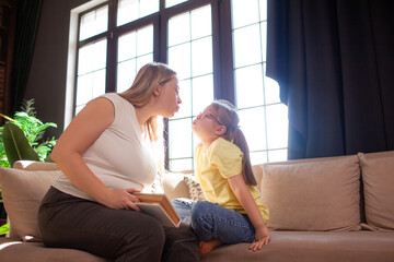 A 7-year-old child in glasses and mother have fun in sofa indoor