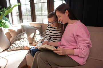 A 7-year-old child in glasses and mother have fun in sofa indoor
