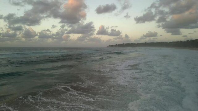 Ocean waves rolling towards tropical beach at sunset