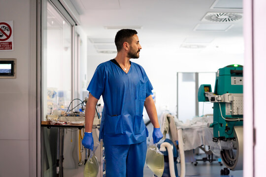Nurse carrying medical waste in hospital corridor - Powered by Adobe