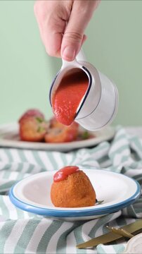Hot tomato sauce poured over crispy Sicilian arancini. Traditional Italian rice balls served fresh. Food motion close-up. High quality FullHD footage