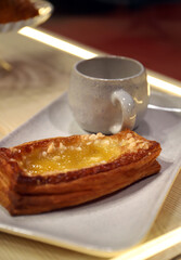 desayuno con una taza de cerámica y un bollo de hojaldre con crema de cabello de ángel