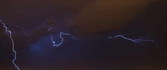 Lightning discharge during a hurricane over a night city. Concept on the theme of natural phenomena, weather, etc.